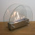Circular tabletop fireplace wit glass panels on the sides